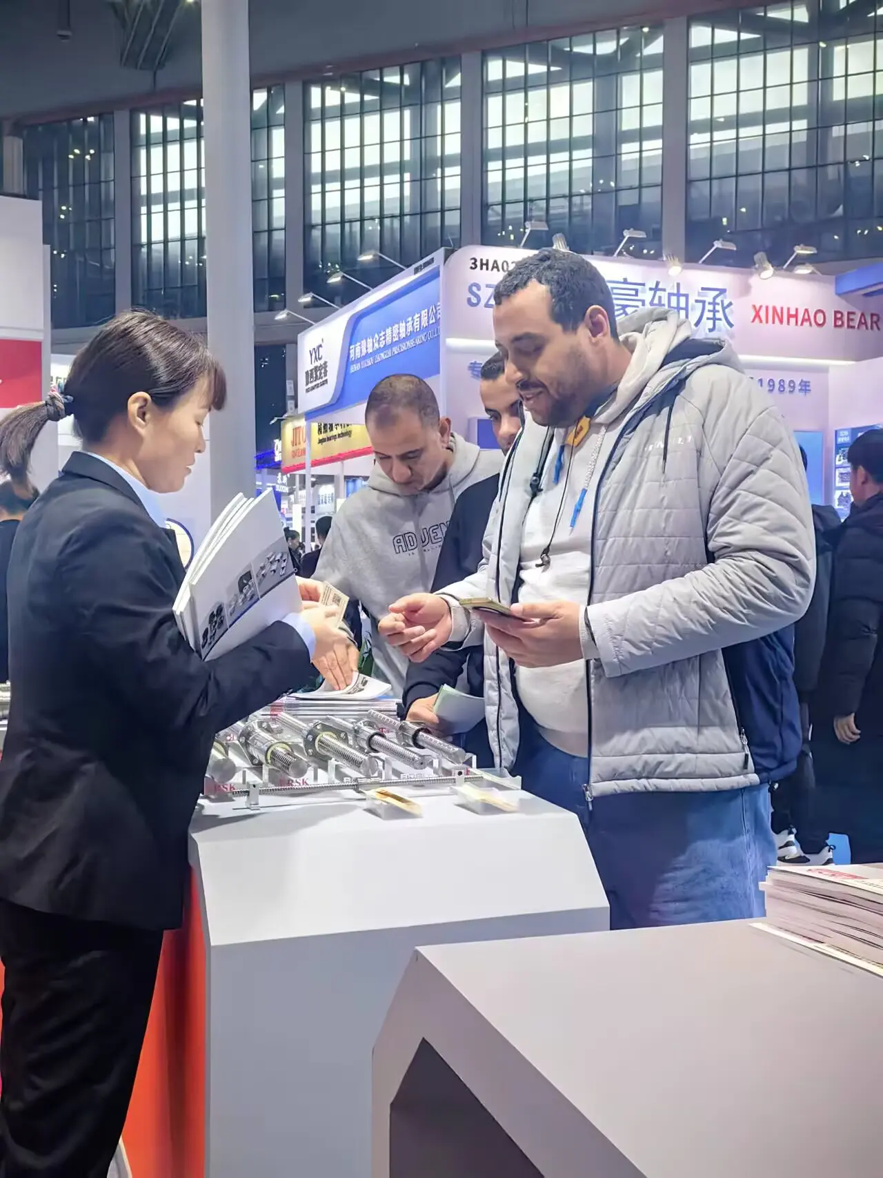 A Wangong team member shows product materials and precision transmission components to visitors at the exhibition booth.